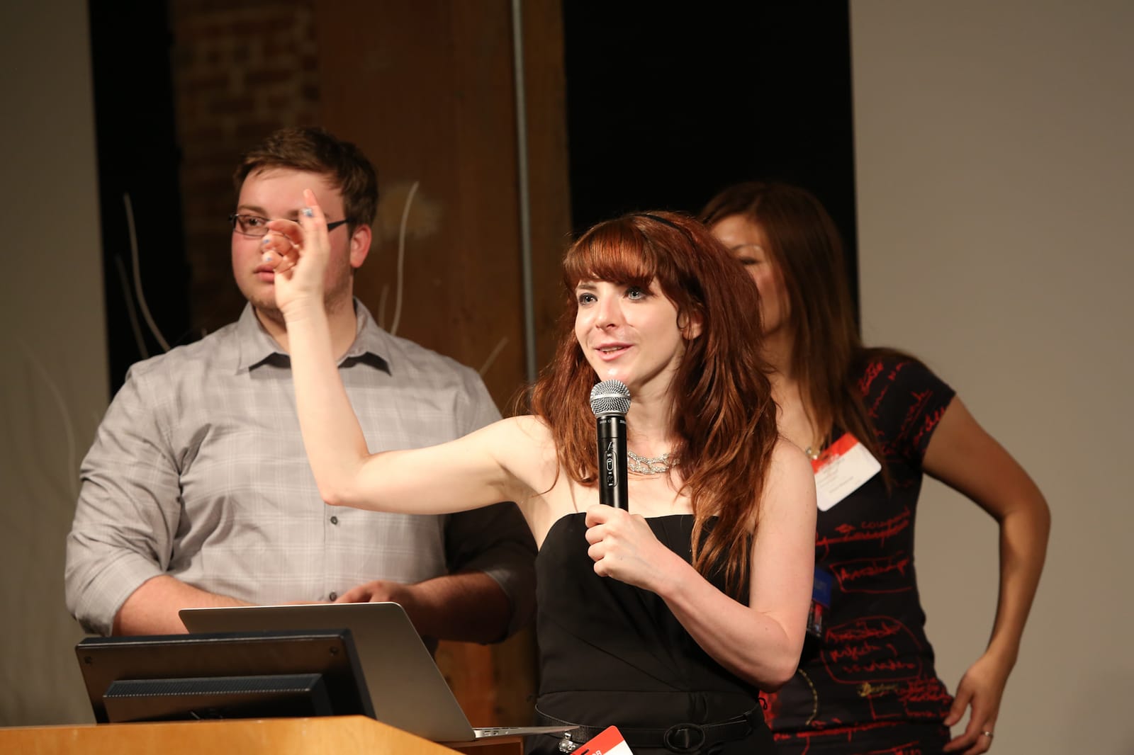 Andi Galpern on stage with a handheld microphone, gesturing mid-talk