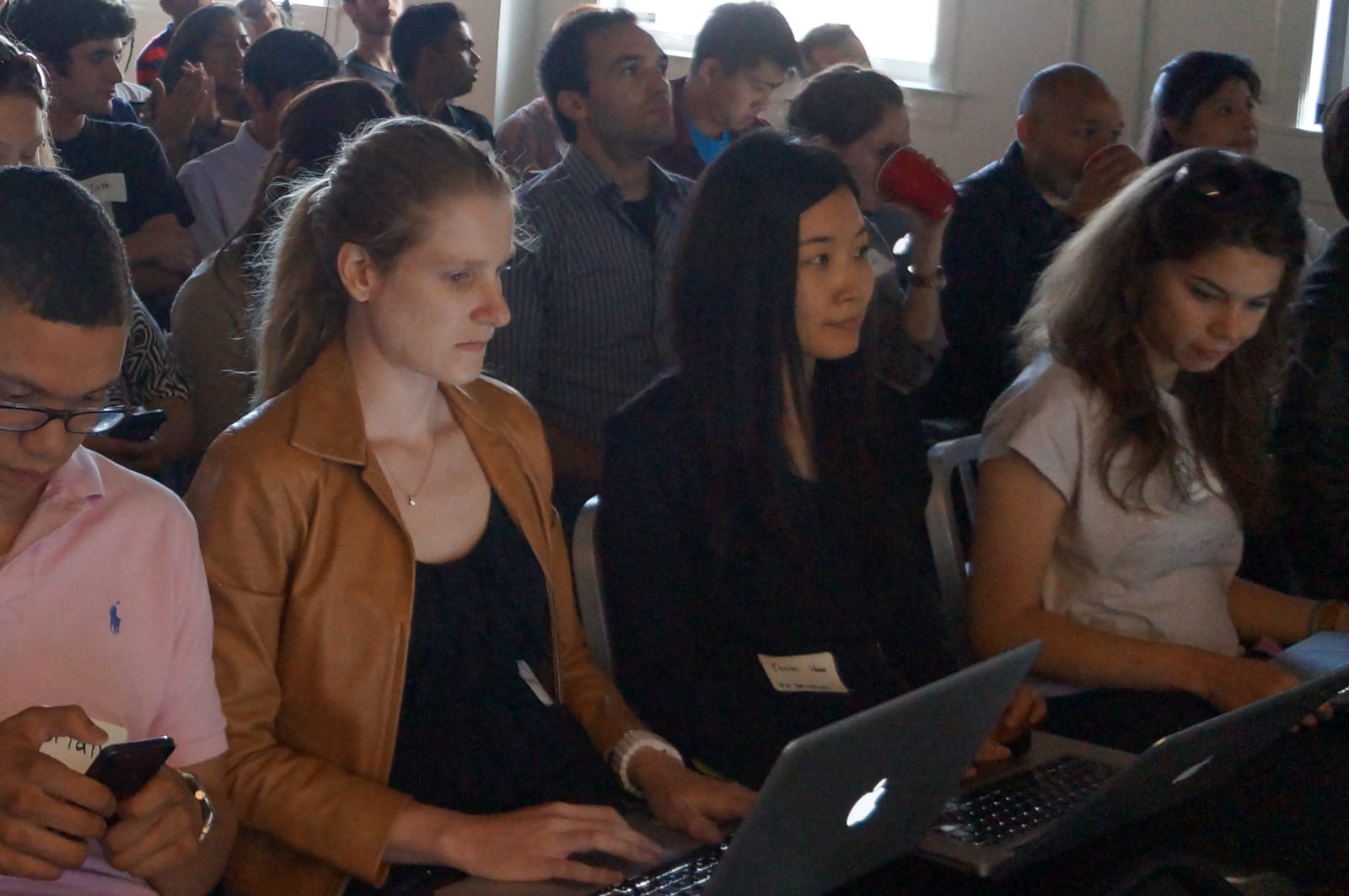 Attendees working on laptops in the audience during a talk