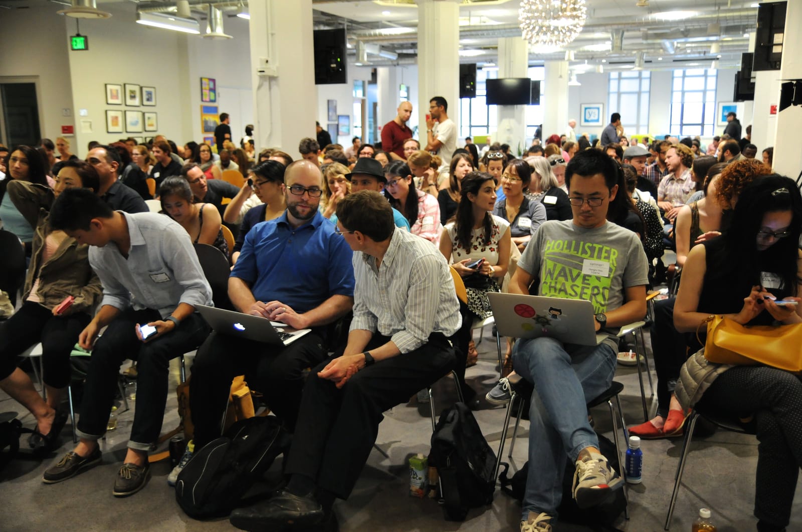 Large audience seated with laptops open in an open loft event space