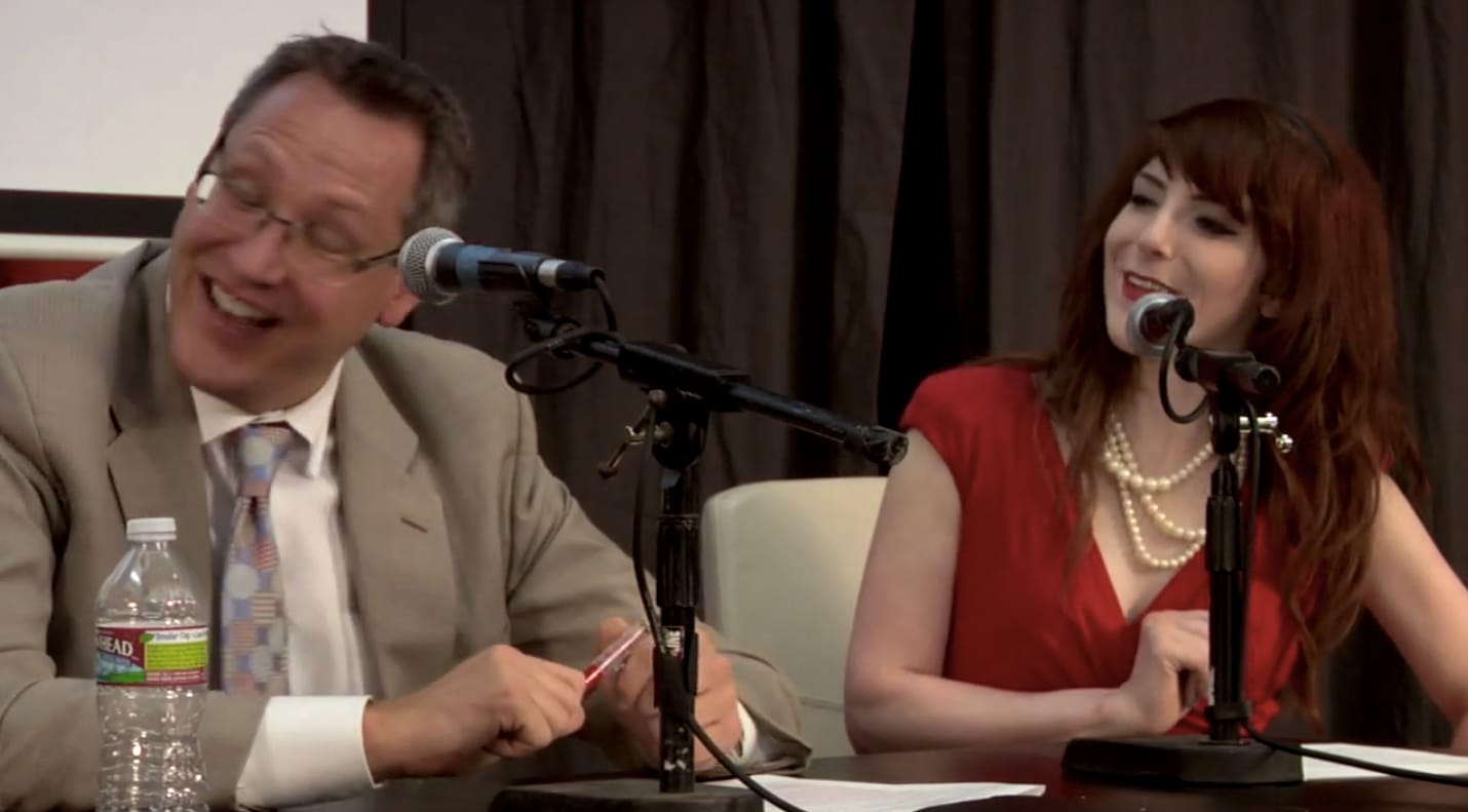 Andi Galpern laughing beside a co-panelist at the microphones during a panel discussion