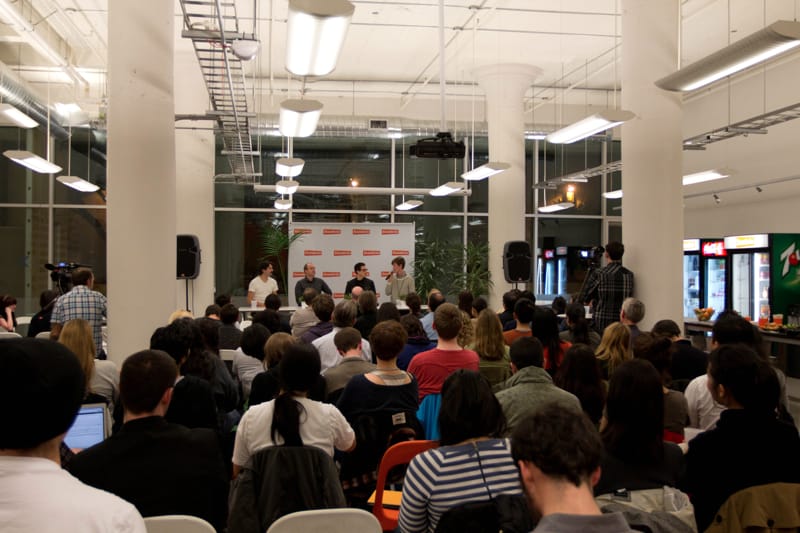 Four panelists on stage in front of an orange backdrop with a full audience seated at a Cascade SF event